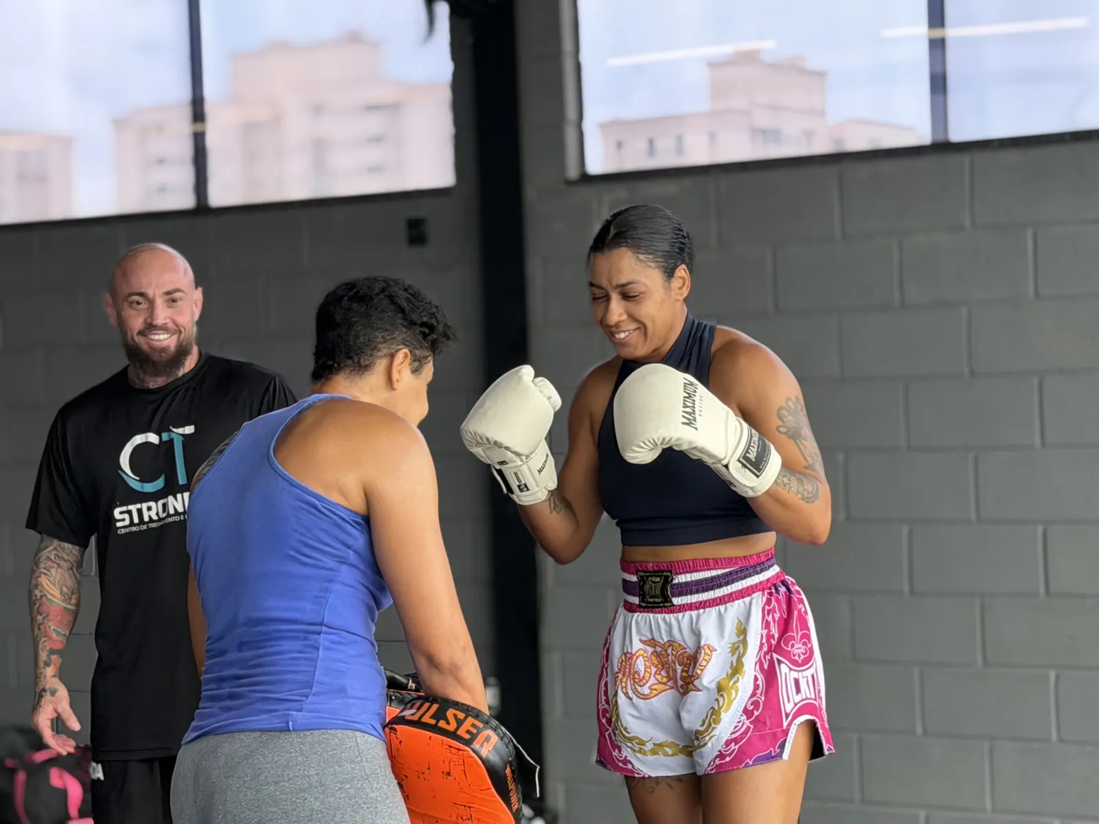 Professor ajustando a guarda de uma aluna no Muay Thai do CT Stronda